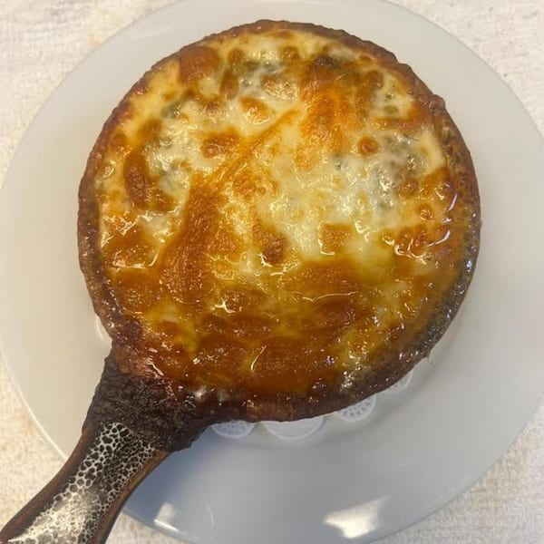 Monalisia's baked Italian dish with melted, bubbly cheese in a small skillet on a white plate.