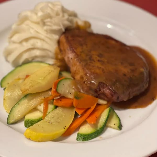 Monalisia's Italian dish with a steak in brown sauce, pasta, and sautéed zucchini and carrots.