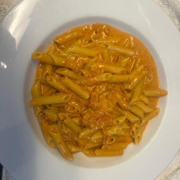 Monalisia's penne pasta in a creamy orange sauce, served in a white bowl.
