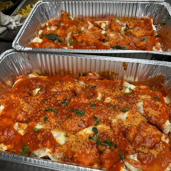Two aluminum trays filled with Monalisia's baked Italian manicotti, topped with red sauce, cheese, and herbs.